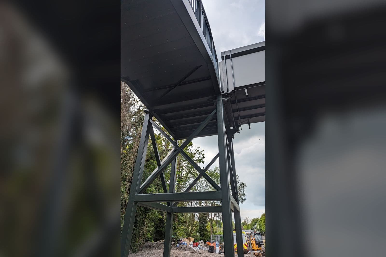 Looking up at the underside of a footbridge deck and the steelwork supporting it.